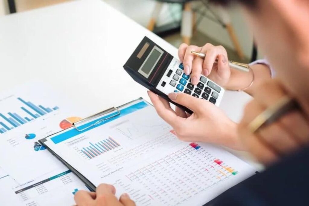 Imagem de duas pessoas calculando em uma calculadora.